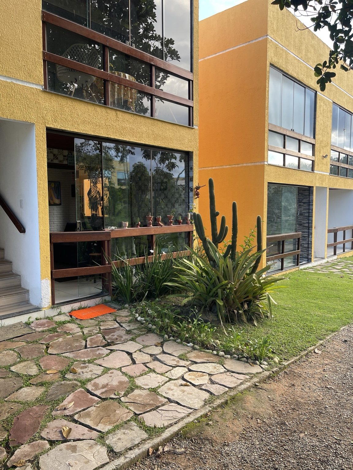 Fachada amarela do condomínio com paisagismo
