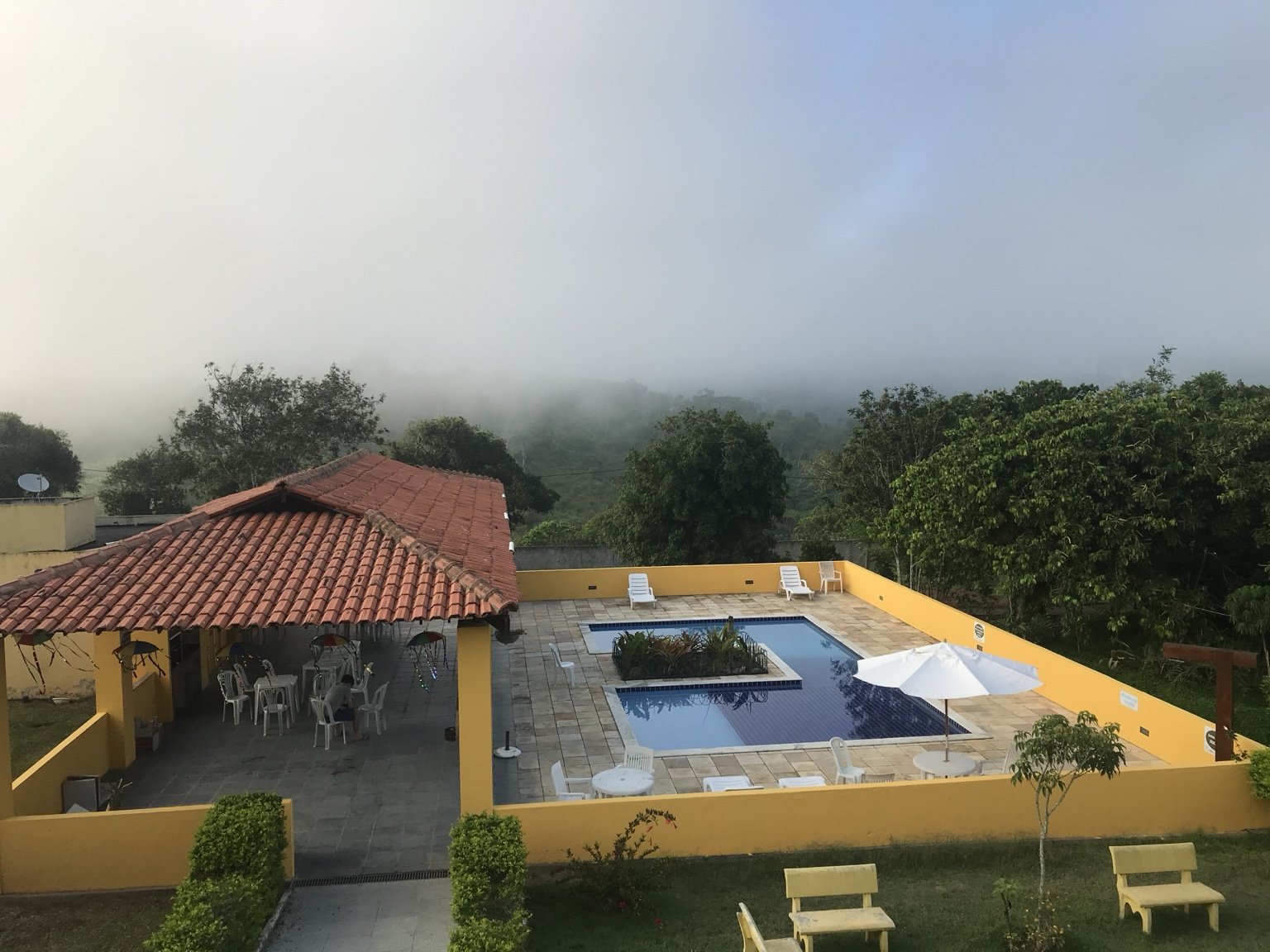 Piscina do condomínio e paisagem serrana com neblina