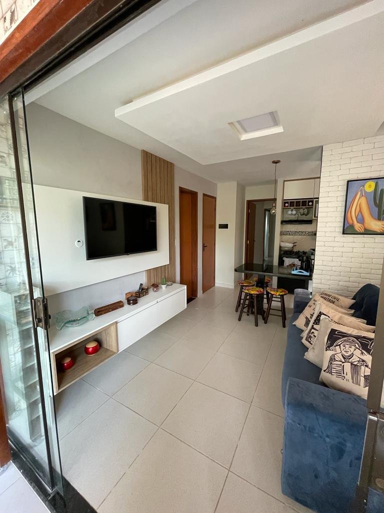 Sala de estar do Flat 16, com sofá, TV e cozinha integrada